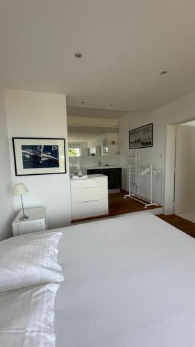 a white bedroom with a large bed and a kitchen at Paradis sur l'Aber in Landéda