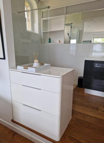 a kitchen with white drawers and a mirror at Paradis sur l'Aber in Landéda