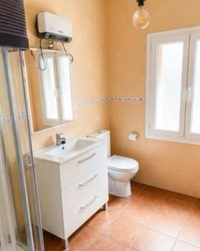 a bathroom with a toilet and a sink and a window at Apartamentos Las Fuentes in Labajos