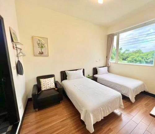 a room with two beds and a chair and a window at Ferry Bow in Jincheng