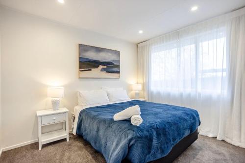 a bedroom with a bed with a blue blanket and a window at Roslyn Sanctuary Hereford St Dunedin in Dunedin