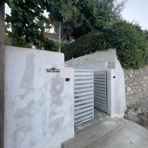 a white fence with a gate next to a wall at Saint Giovanni House in Kharokopión