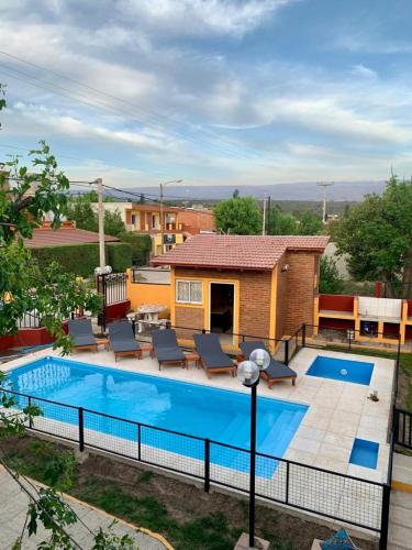 a swimming pool with chairs and a house at Complejo sierras de brochero in Villa Cura Brochero