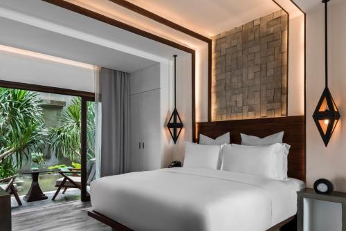 a bedroom with a white bed and a large window at Jaya House River Park in Siem Reap