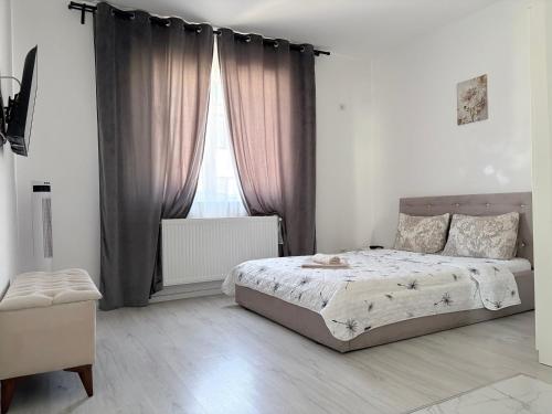 a bedroom with a bed and a window with curtains at Bella Home Residence in Roşu