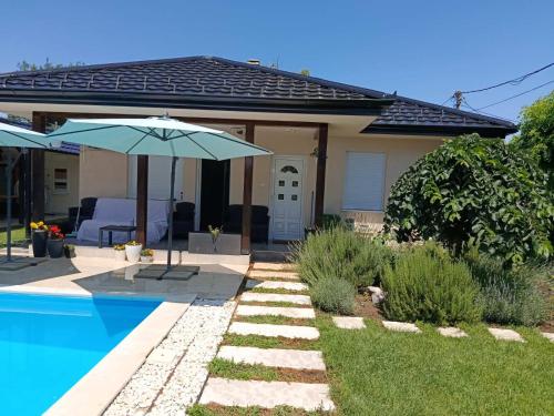 a house with a swimming pool and an umbrella at MARINA HOUSE pool & garden in Beograd