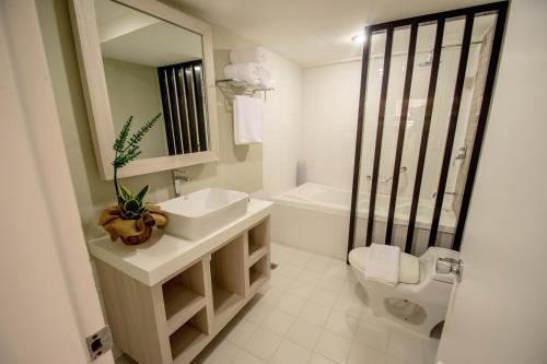 uma casa de banho com um lavatório, um WC e um espelho. em Almont City Hotel em Butuan