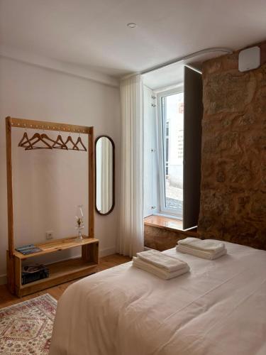 a bedroom with a bed with a mirror and a window at Sobrado das Marias in Figueiró dos Vinhos