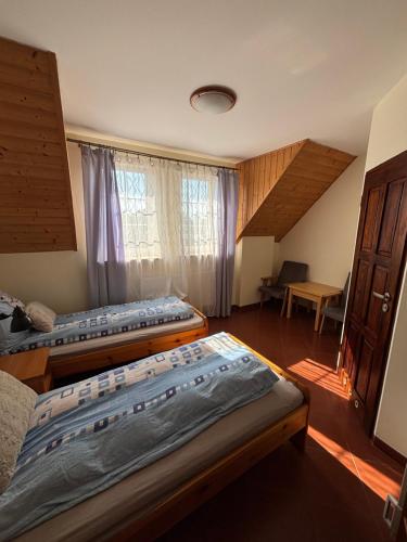 a room with two beds and a table and a window at Pensjonat Dom Latarnika in Grzybowo