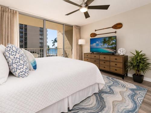 a bedroom with a white bed and a flat screen tv at Royal Kahana 318 Studio Condo in Kahana