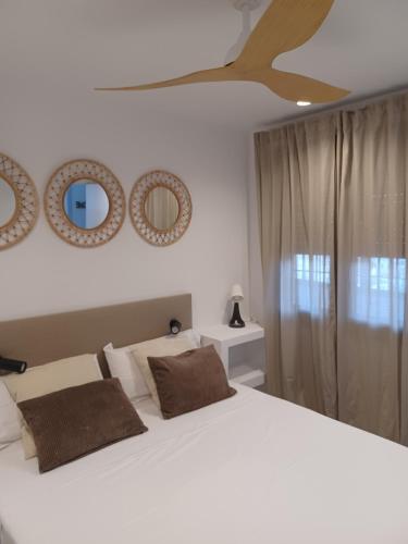 a bedroom with a white bed with two mirrors on the wall at Rosa de los Vientos 71 Renovado julio 2026 in Mijas Costa