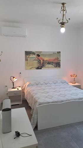 a white bedroom with a bed and a painting on the wall at B&B MAST Apartment Suite in San Pellegrino Terme
