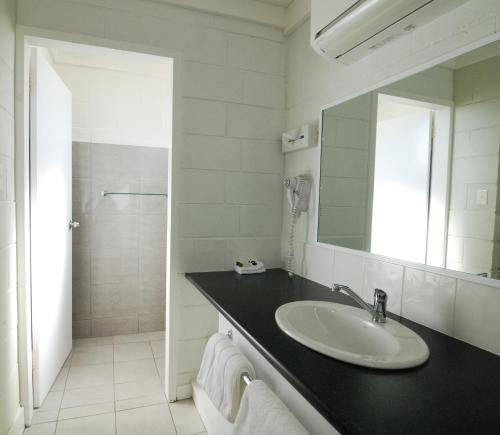 ein weißes Badezimmer mit einem Waschbecken und einem Spiegel in der Unterkunft Mayfair Motel in West Wyalong