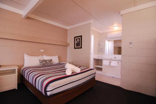 a bedroom with a bed and a small bathroom at Mayfair Motel in West Wyalong