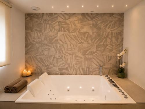 a bath tub in a bathroom with a stone wall at Sweet Home & Spa in Erstein
