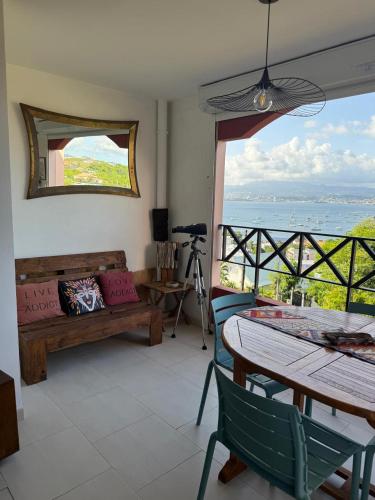 a living room with a table and a view of the ocean at Flamingo Bay in Les Trois-Îlets
