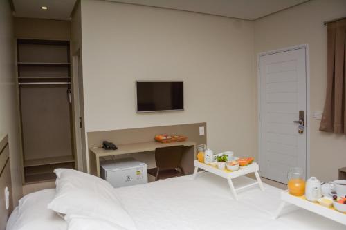 a bedroom with a bed and a desk and a tv at Hotel Imperador in Gurupi