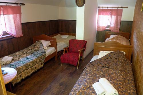 a hotel room with two beds and a red chair at Etno Resort Lipa 