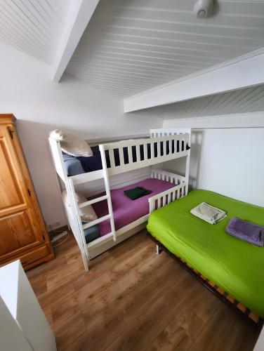 a bedroom with two bunk beds and a green mattress at Villa 16 personnes à 50m plage Sud in Lacanau