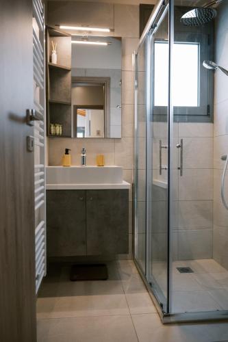 a bathroom with a sink and a glass shower at Odysseas Seaside Escape by Philoxenia in Artemida