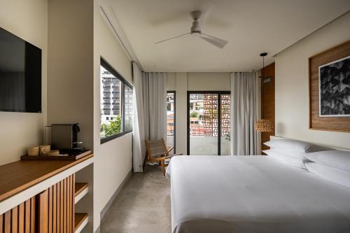 a bedroom with a white bed and a tv and window at The Tryst Puerto Vallarta LGBT Hotel in Puerto Vallarta