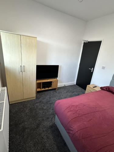 a bedroom with a bed and a cabinet and a tv at Plus Properties Leeds 2 in Bradford