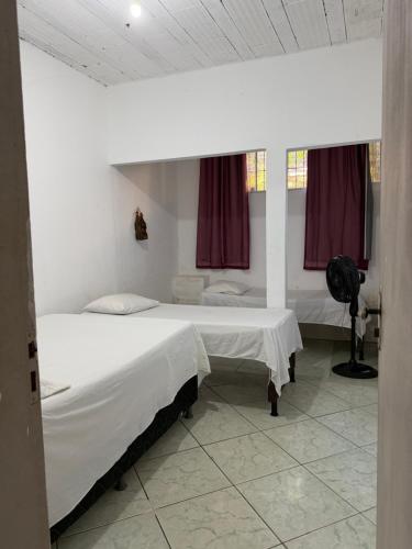 two beds in a room with red curtains at Cantinho do amor in Vitória