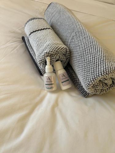 a bed with two bottles of soap and a towel at Alwaba guest house in Mthatha