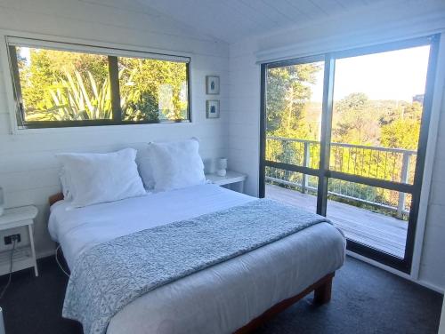 a bedroom with a bed and a large window at Island view Experience in Coromandel Town