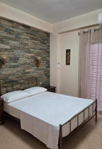 a bedroom with a large bed with a brick wall at Kohil Guest House in Ksamil