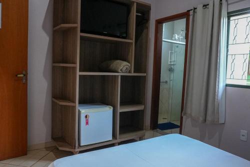 a bedroom with a book shelf with a tv and a bed at Hotel Fazenda Haras RD in Olímpia