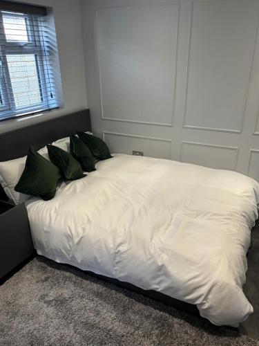 ein weißes Bett mit grünen Kissen in einem Schlafzimmer in der Unterkunft awesome studio flat in Welling