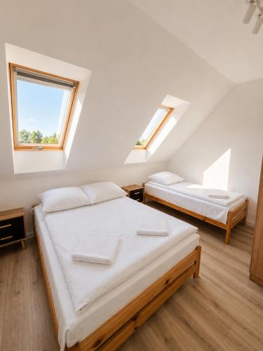 two beds in a room with two windows at Sunrise Marina Domki Mielno- Ferienhaus in Mielenko