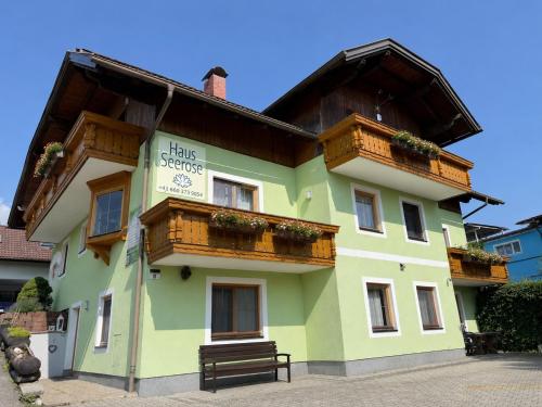 a green building with wooden balconies and a bench at Haus Seerose in Seeboden
