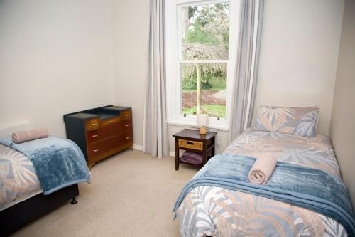 a bedroom with a bed and a dresser and a window at Cath's cottage in Diamond Harbour
