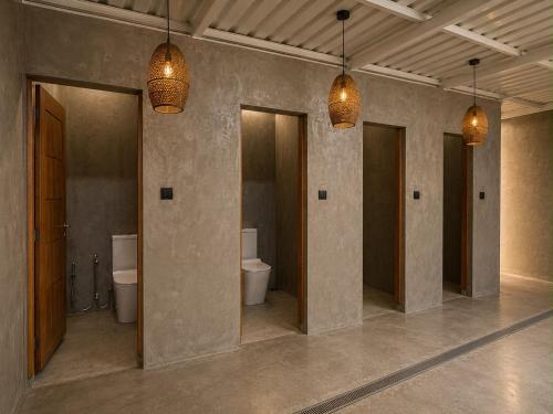 a bathroom with three toilets and three lights at Curve Ahangama in Ahangama