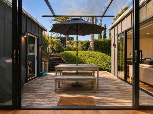 a picnic table with an umbrella on a patio at Art Lovers Retreat - Stay Waiheke in Onetangi