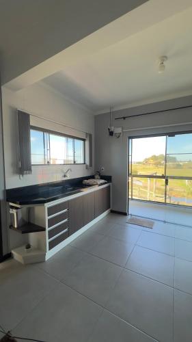 a kitchen with a sink and a large window at Kitnet beira da lagoa in Terra de Areia