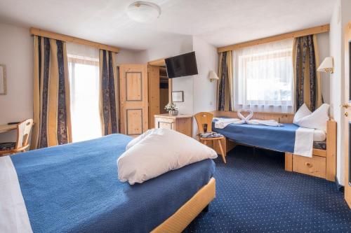 a hotel room with two beds and a television at Hotel Serena in Badia