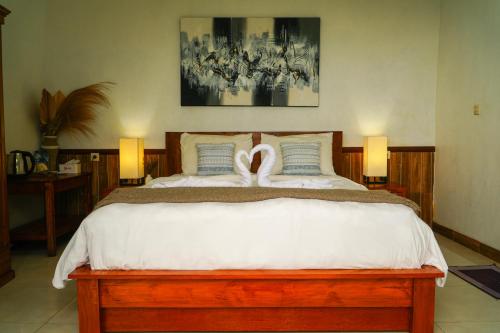 a bedroom with a bed with two swans on it at De Sila House and Pool in Tembuku