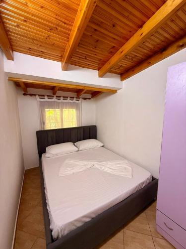 a bed in a small room with a wooden ceiling at Green Door House in Vlorë