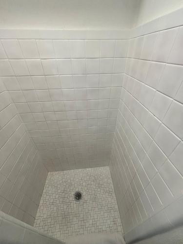 a white tiled shower with a drain in it at Martin House Motel in Brookfield