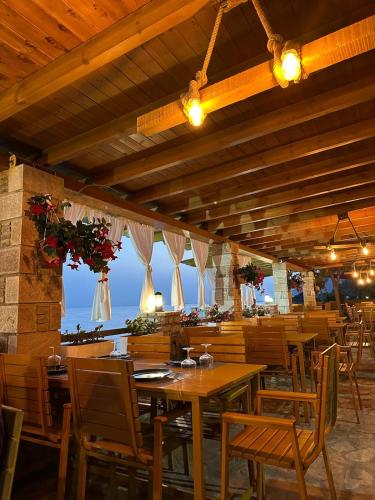 a restaurant with wooden tables and chairs with a view of the ocean at Hotel Brigeni & Camping Riviera in Shëngjin