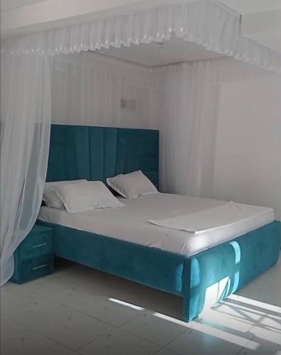 a bed in a room with a blue bed frame at Wrens cosy home in Diani Beach