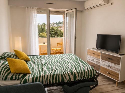 a bedroom with a bed and a tv and a window at Lovely studio with balcony - central location in Cavalaire-sur-Mer