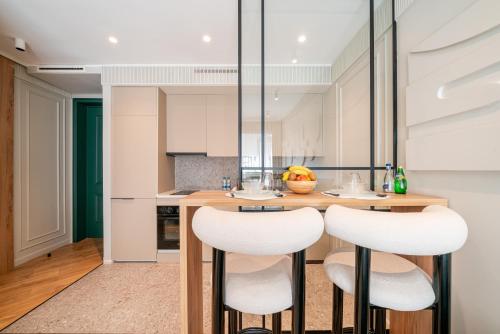 a kitchen with white cabinets and white stools at VIVASTAY Casablanca -Corniche Le claridge Emerauld with gym and rooftop in Casablanca