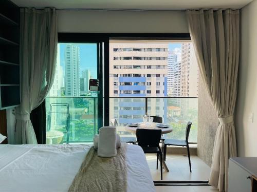 a bedroom with a bed and a table and a large window at Beach Class Meireles by HostFacil in Fortaleza