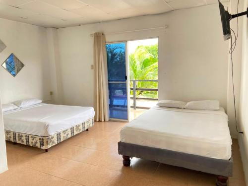 two beds in a room with a window at Hostería del Puerto in Puerto López
