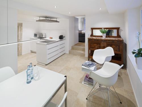 a kitchen with white cabinets and white chairs at Domresidenz Regensburg in Regensburg