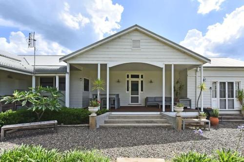 a white house with benches in front of it at La Sila Homestead on Marrowbone in Mount View